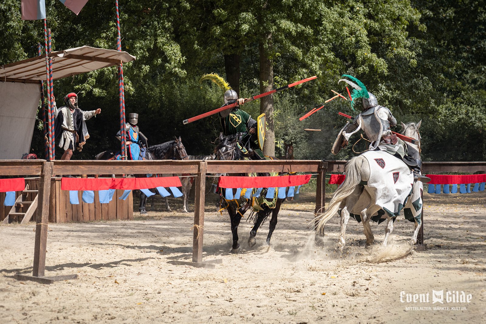 Zwei Ritter treffen im Lanzengang aufeinander, daneben der Turniermarschall an der Bande des ANNO 1238 in Telgte