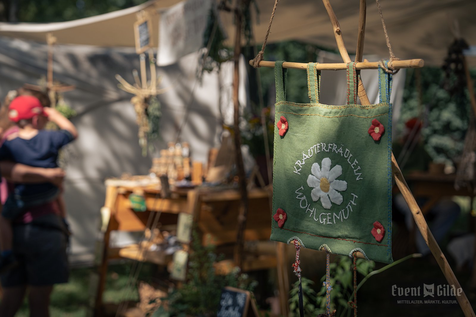 Grünes Banner vom Kräuterfräulein Wohlgemuth mit Margeritenmotiv vor dem Kräuterstand in Telgte